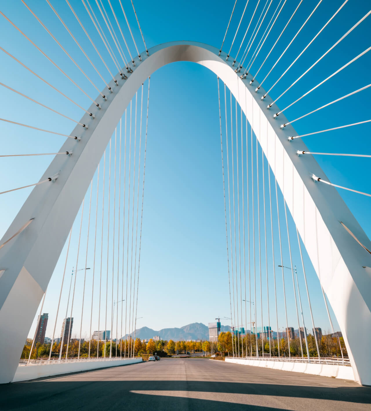White arch over a bridge overlooking a blue sky.